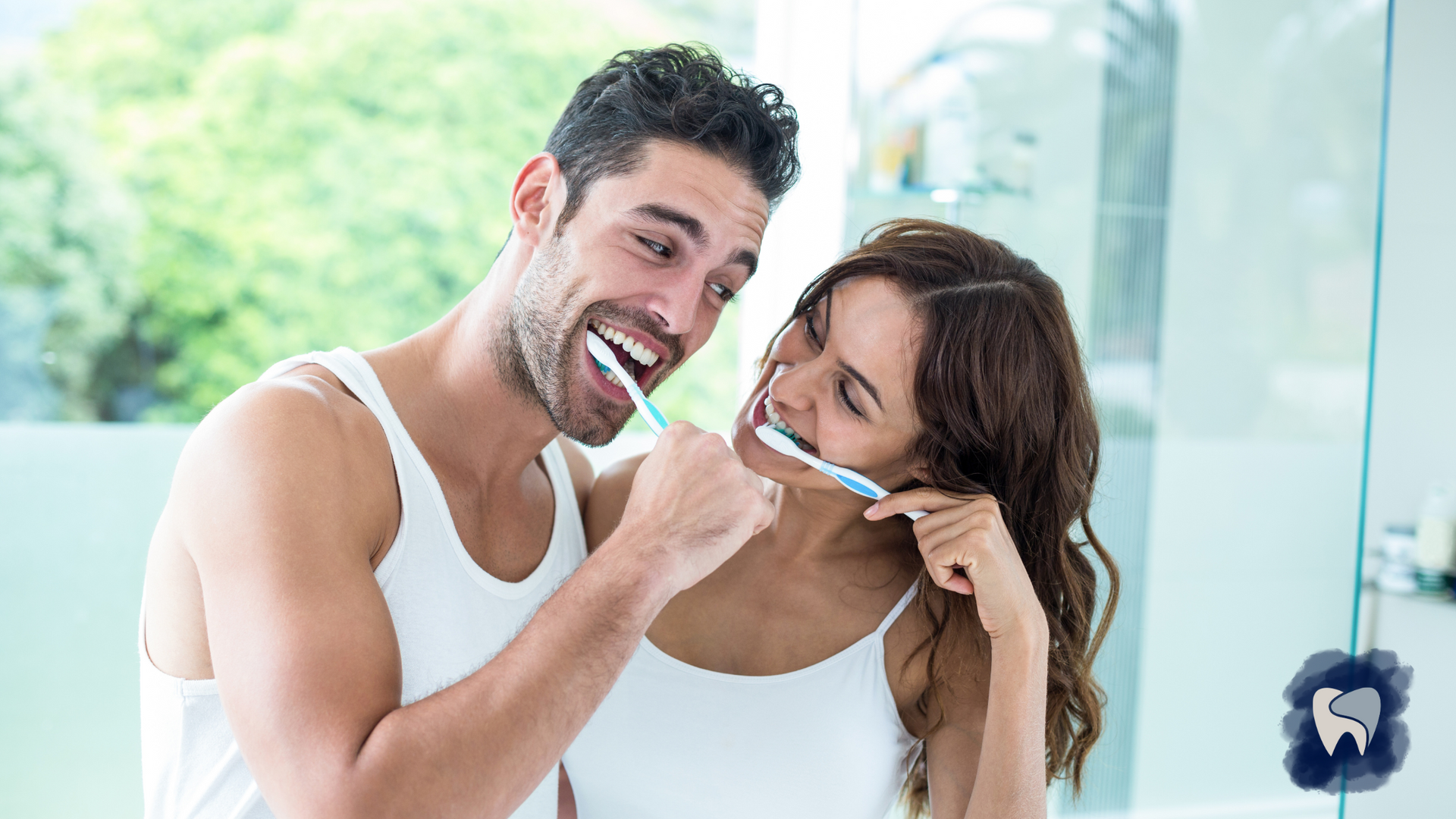 A man and a woman are brushing their teeth together in front of a mirror.