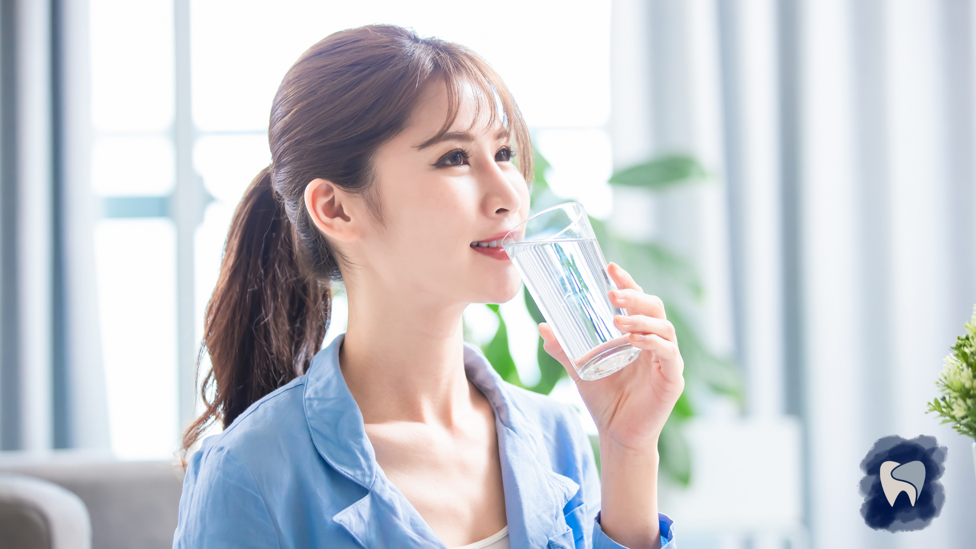 A woman is drinking a glass of water in a living room.