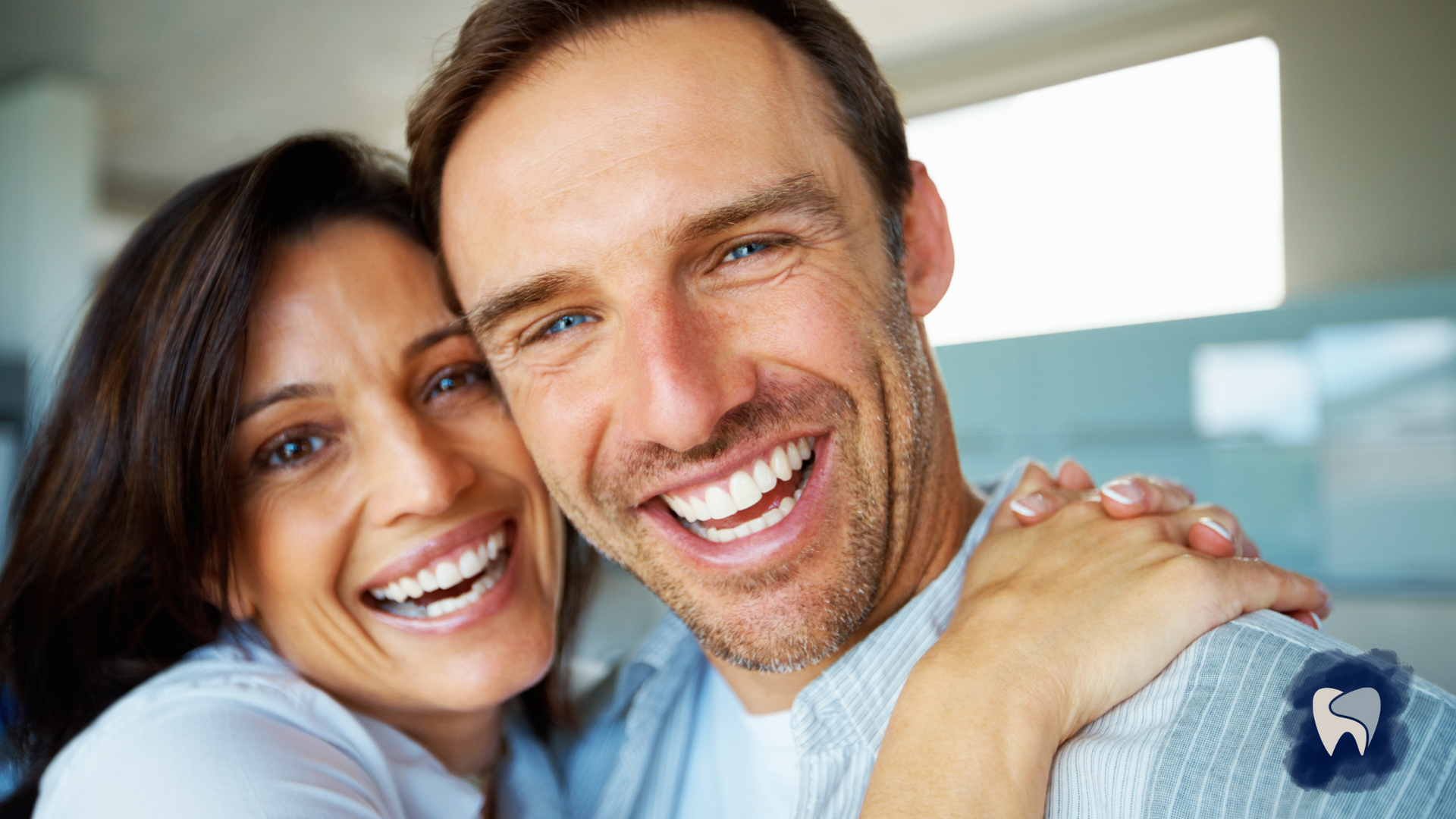 A man and a woman are hugging each other and smiling for the camera.