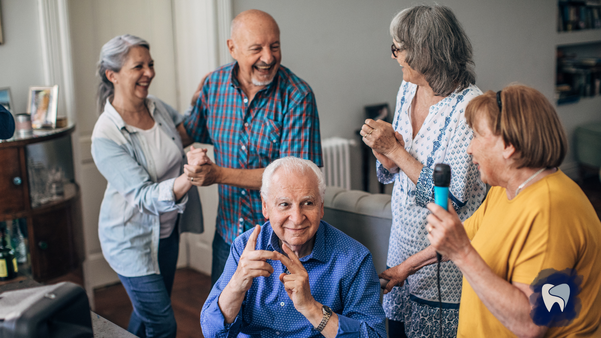 A group of elderly people are dancing and singing into microphones in a living room.