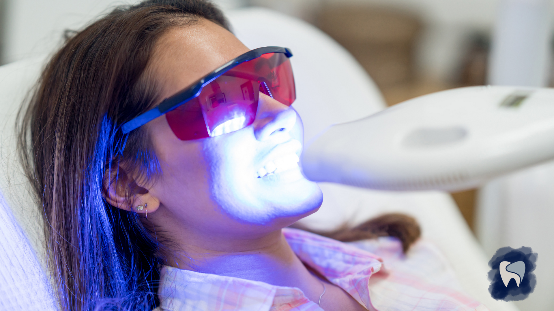 A woman is getting a teeth whitening treatment at a dental office.