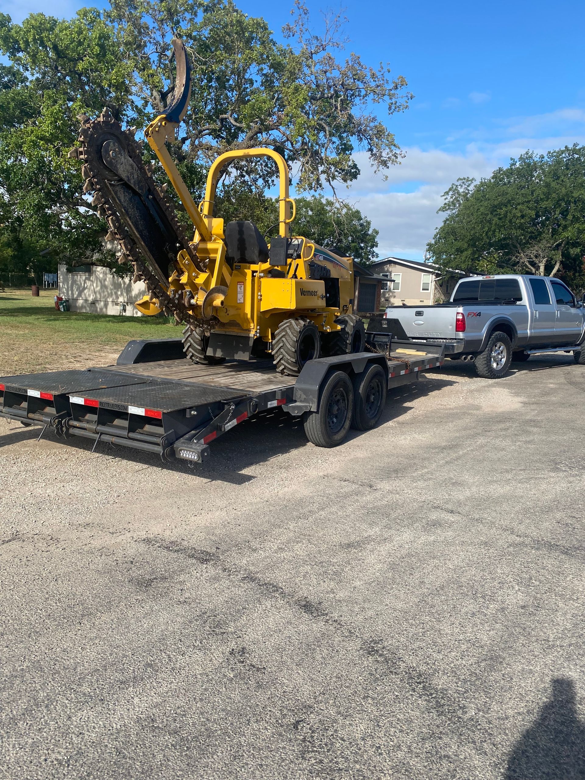 A yellow tractor is being towed by a truck on a trailer.