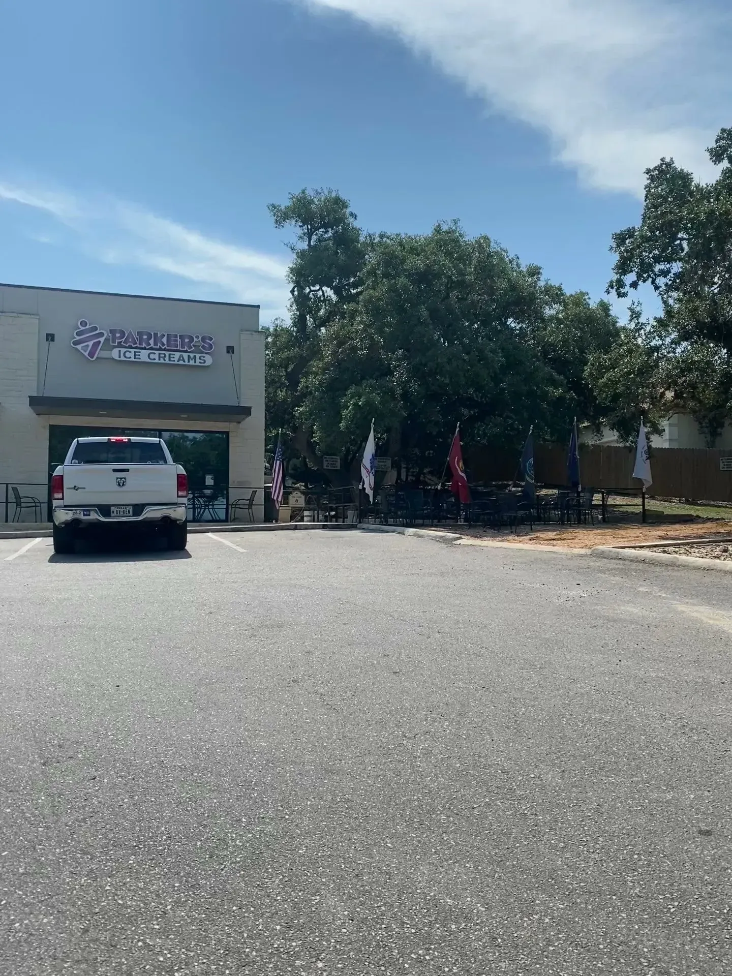 A restaurant with a white truck parked in front; outdoor seating visible under a large tree.
