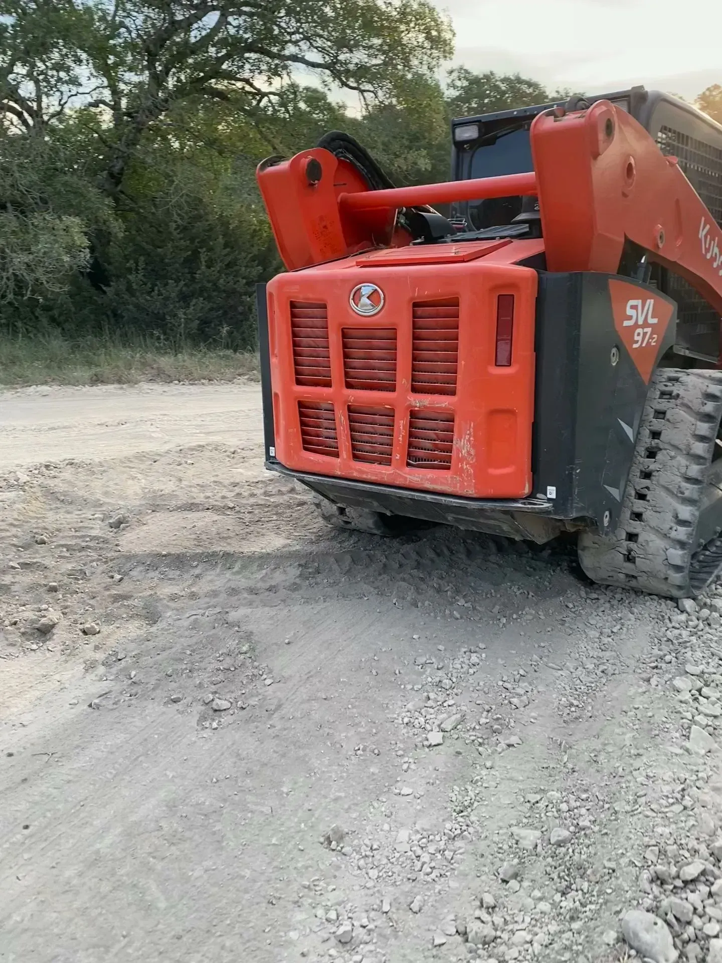 Orange Kubota SVL 75-2 skid steer loader on a gravel surface.