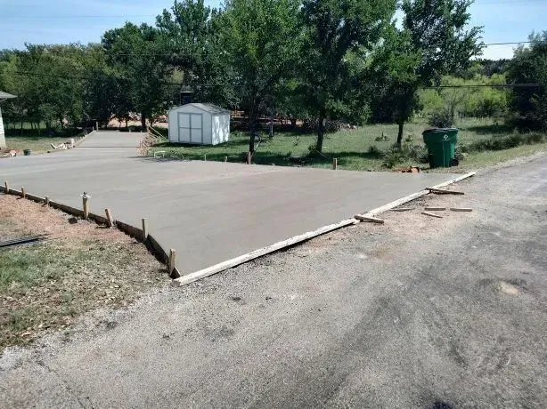Newly poured concrete driveway with wooden forms, in a grassy residential area.