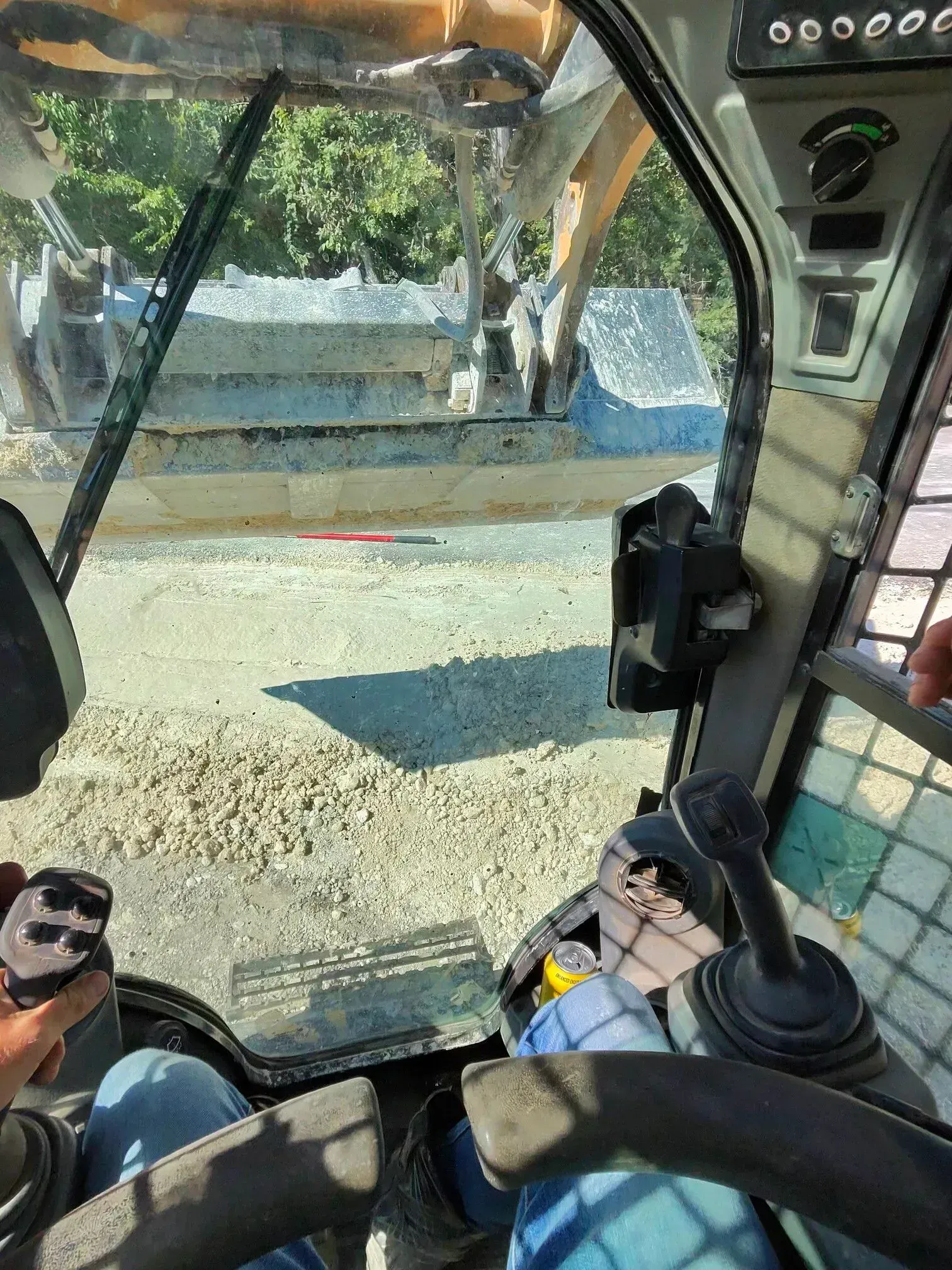 View from inside a construction vehicle cab, looking out at a work site.