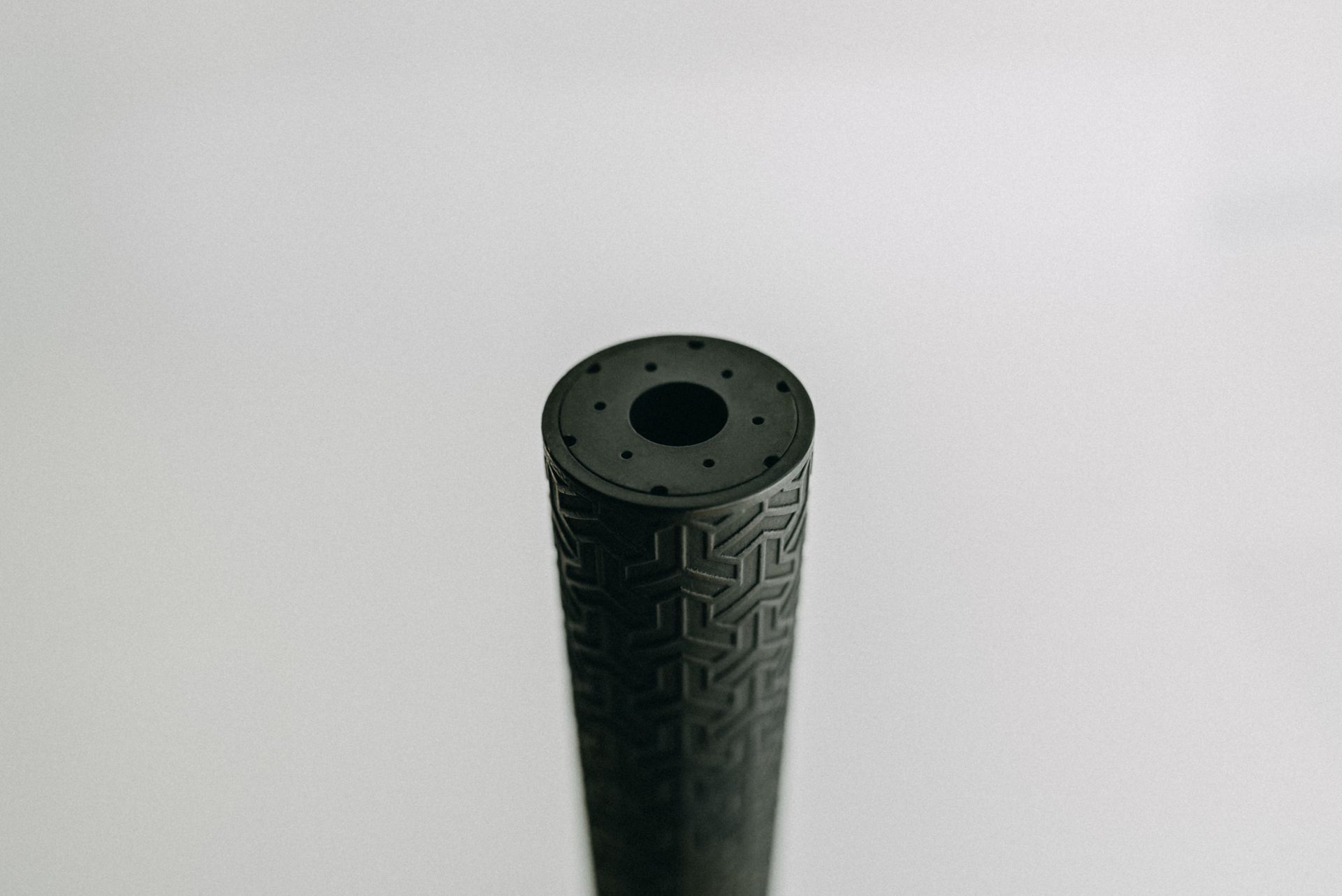 A close up of a black cylinder with a hole in the middle on a white surface.