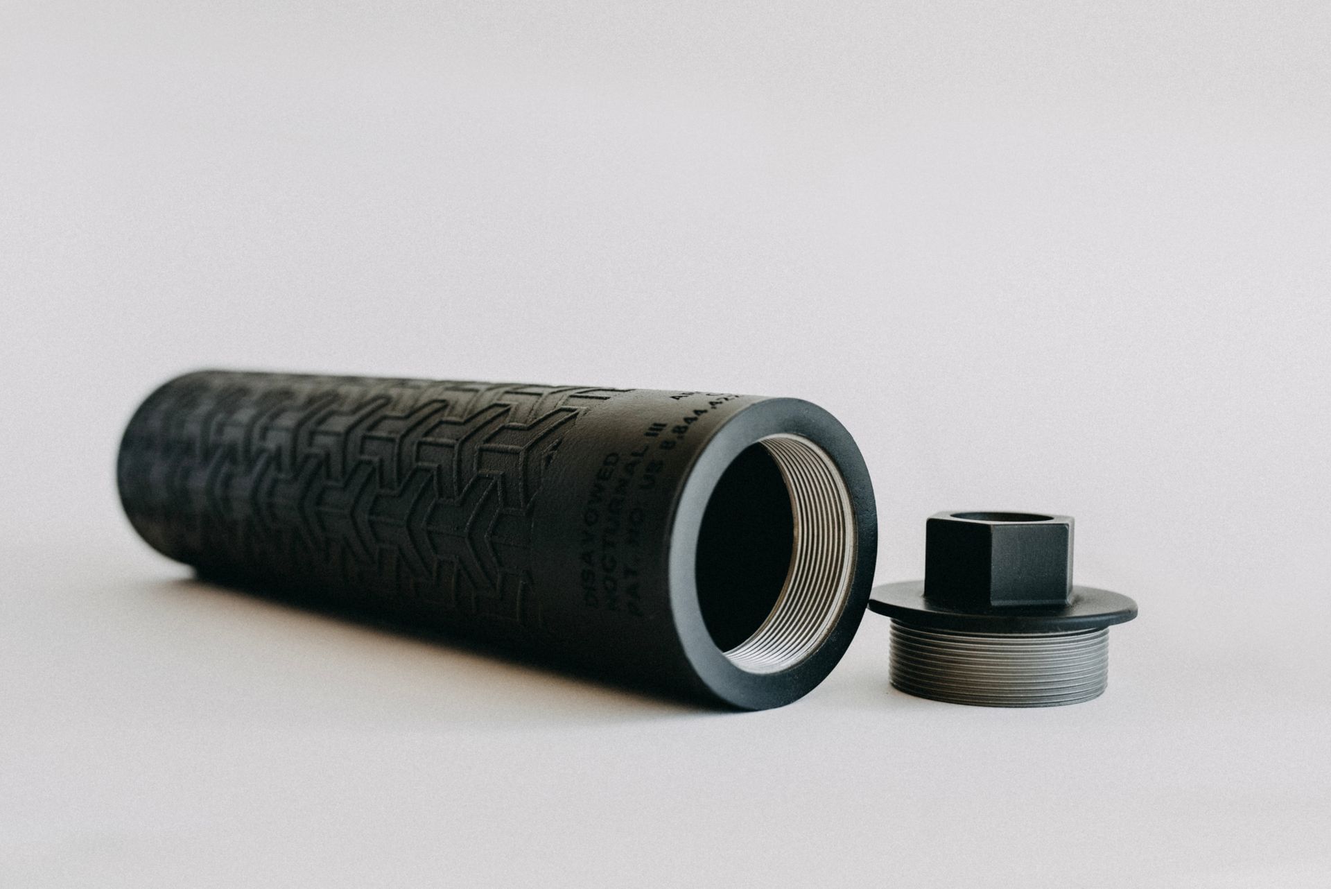 A black cylinder with a hole in the middle is sitting on a white surface.