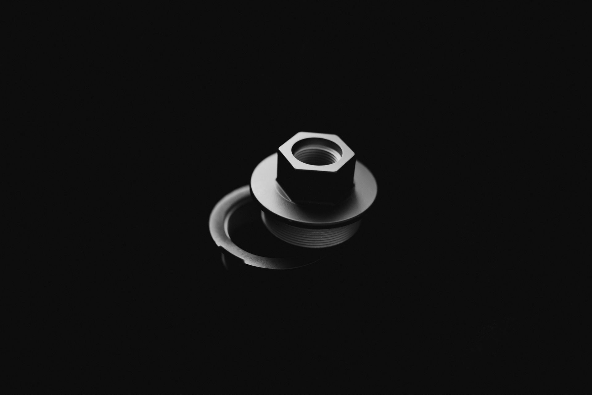 A black and white photo of a nut and washer on a black background.