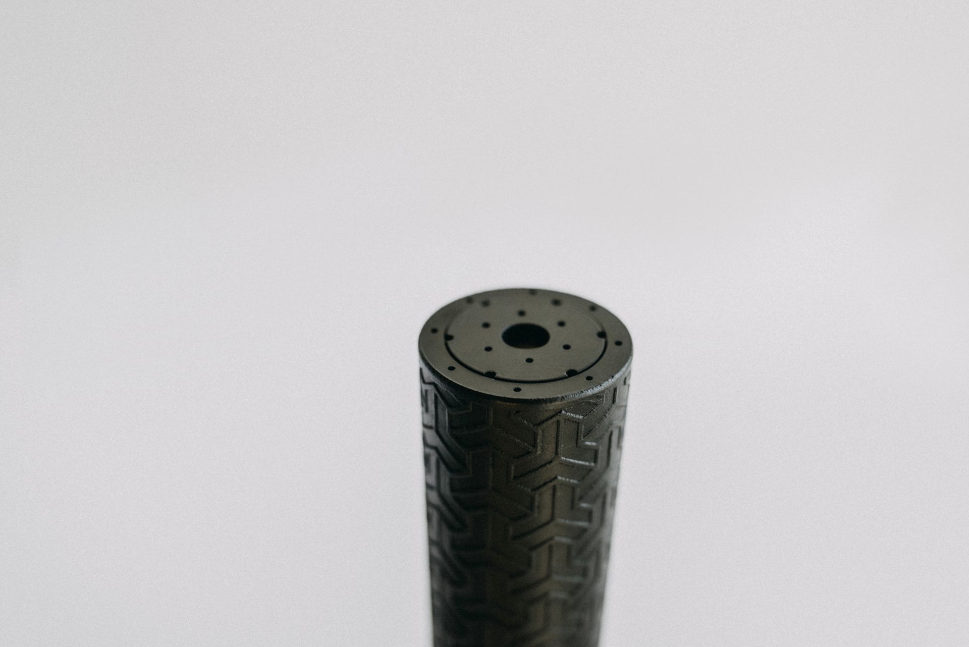 A close up of a black cylinder with a hole in the middle on a white surface.