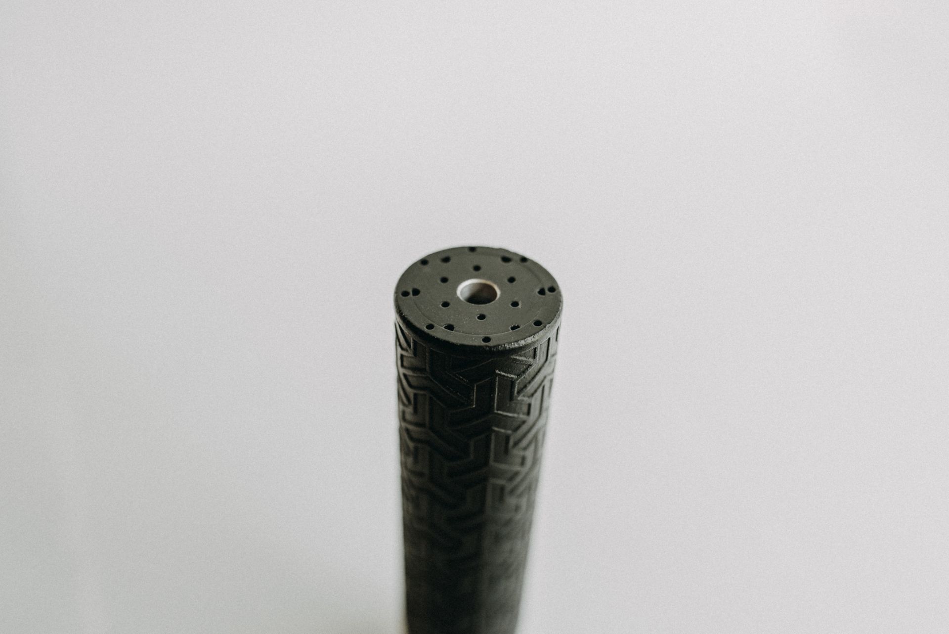 A close up of a black cylinder with a hole in the middle on a white surface.