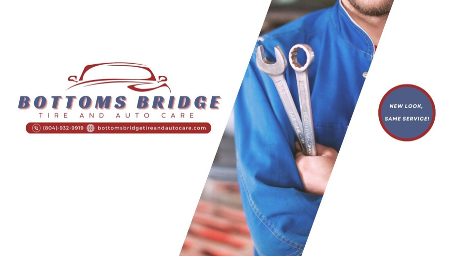 A man is holding two wrenches in front of a sign that says bottoms bridge tire and auto care