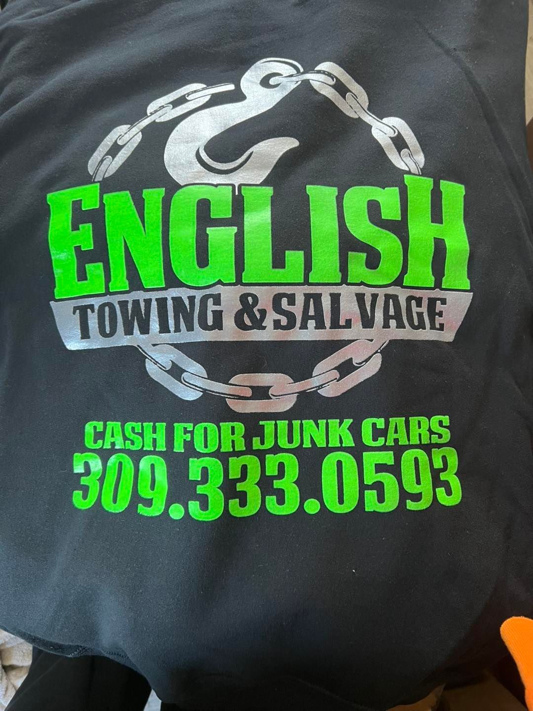 Black sweatshirt with green and silver logo for English Towing & Salvage with phone number.