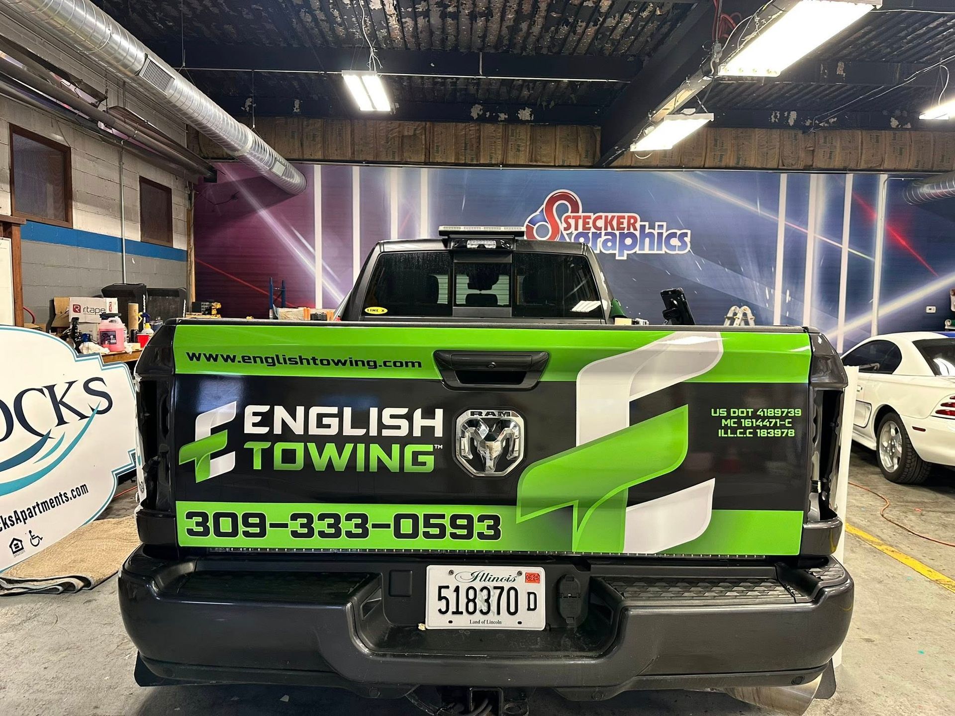 Back of a black English Towing truck with green and white graphics, license plate 51837D.