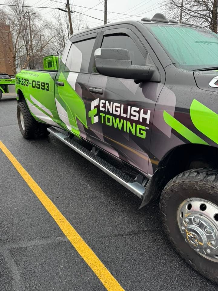 A green and black English Towing truck parked on a road.