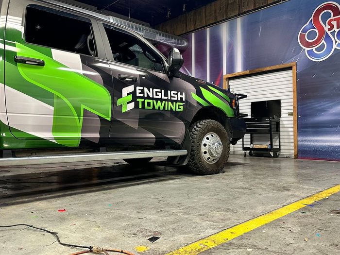 English Towing truck in a garage with green and black camouflage wrap.
