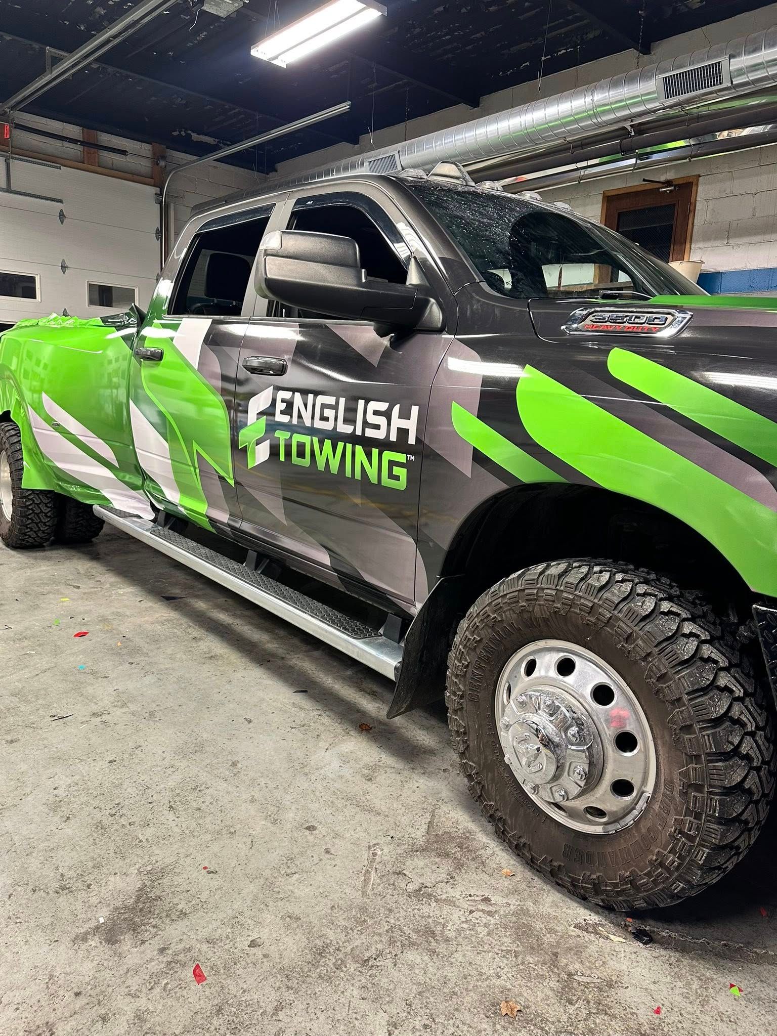 Black and green English Towing truck parked in a garage.