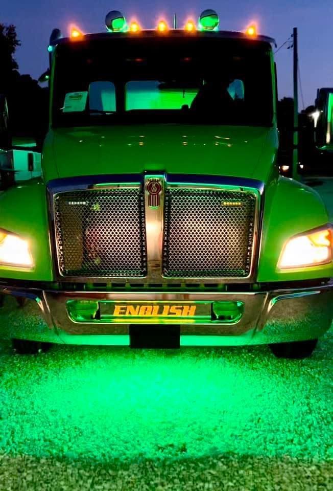 Green semi-truck lit up with green lights at night. 