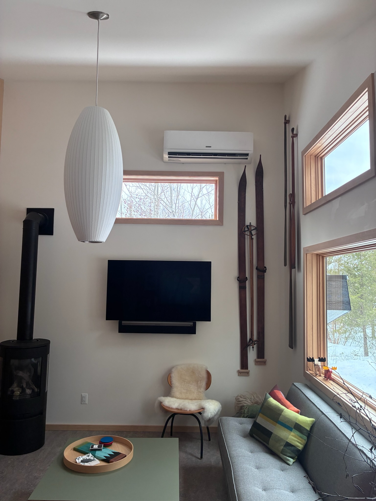 A large, rectangular HVAC unit suspended in the air by cables, over a building and parking lot, blue sky background.