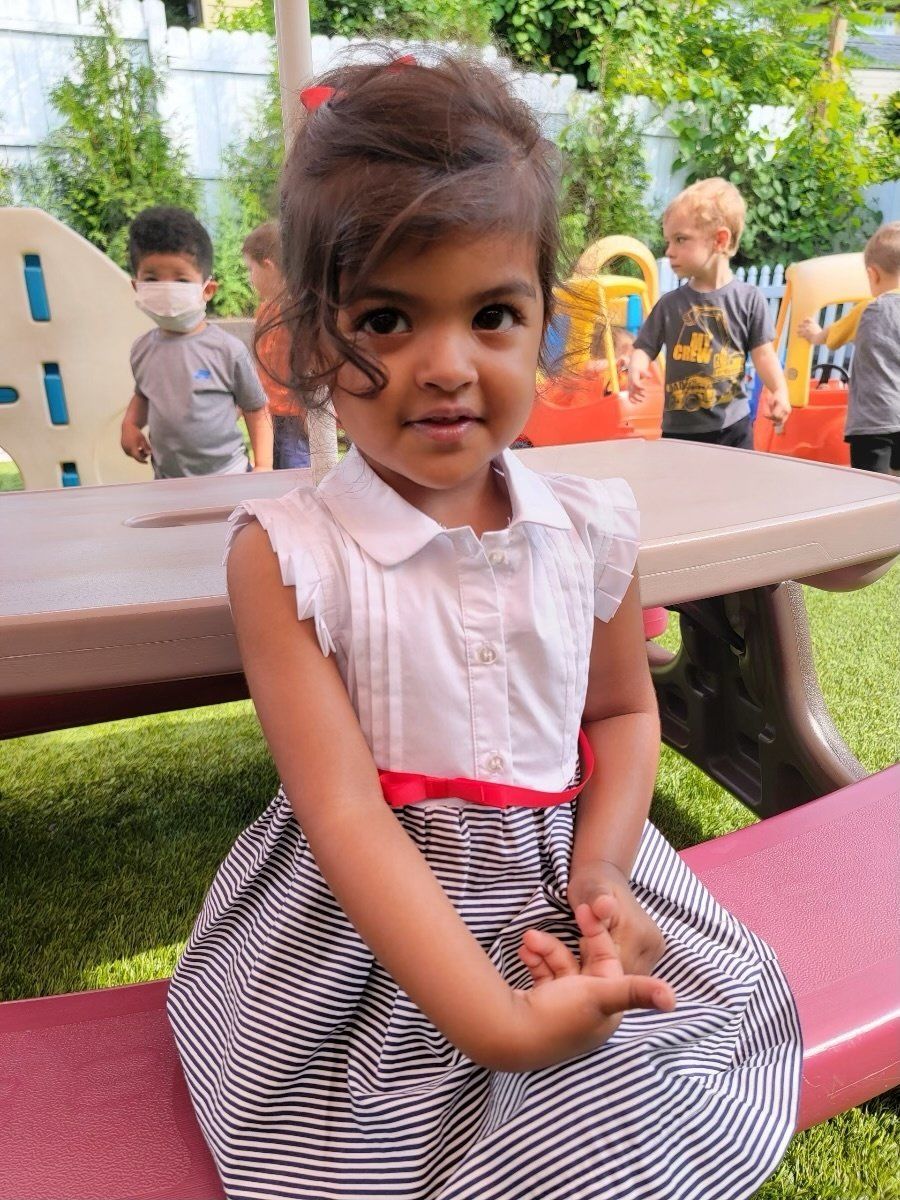 a little girl sitting at a picnic table