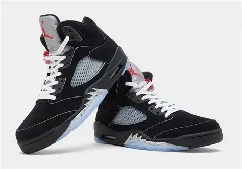Black and gray Air Jordan 5 sneakers with red accents and white laces, set against a white backdrop.