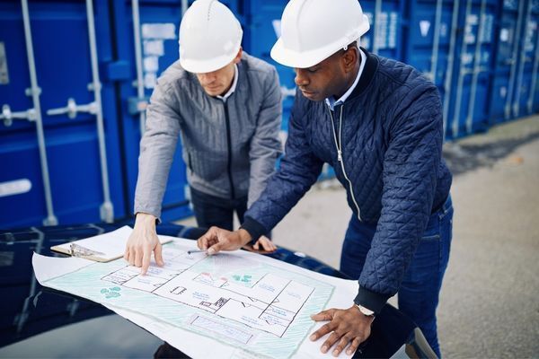 Two men in hard hats are looking at a blueprint.