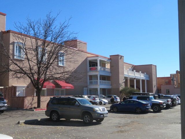 A row of cars are parked in front of a building