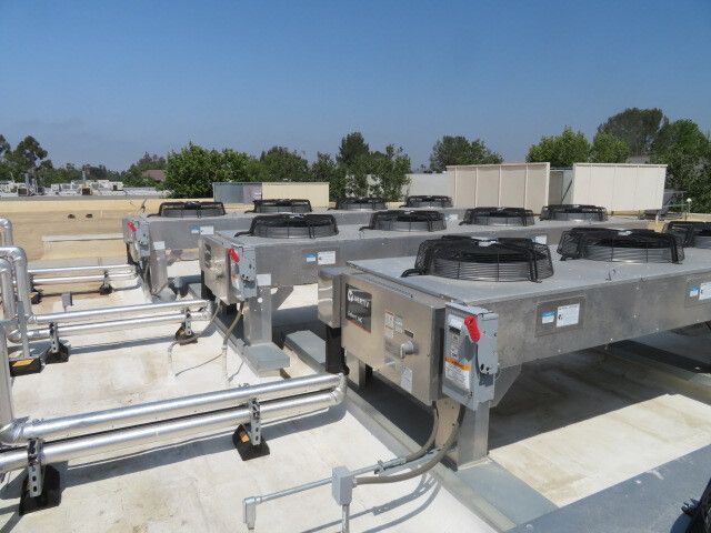 A row of air conditioners are lined up on the roof of a building