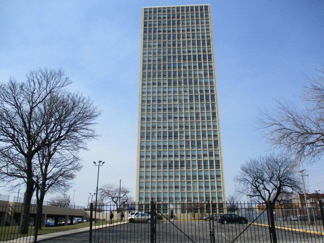A tall building with a lot of windows is behind a fence