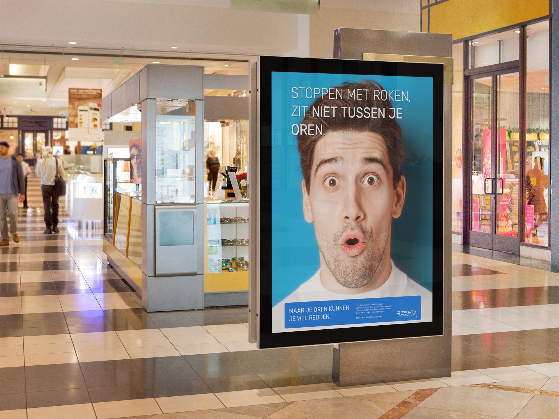 Een man met een verbaasde blik op een poster in een winkelcentrum. Bovenaan staat Nederlandse tekst, op een turquoise achtergrond.