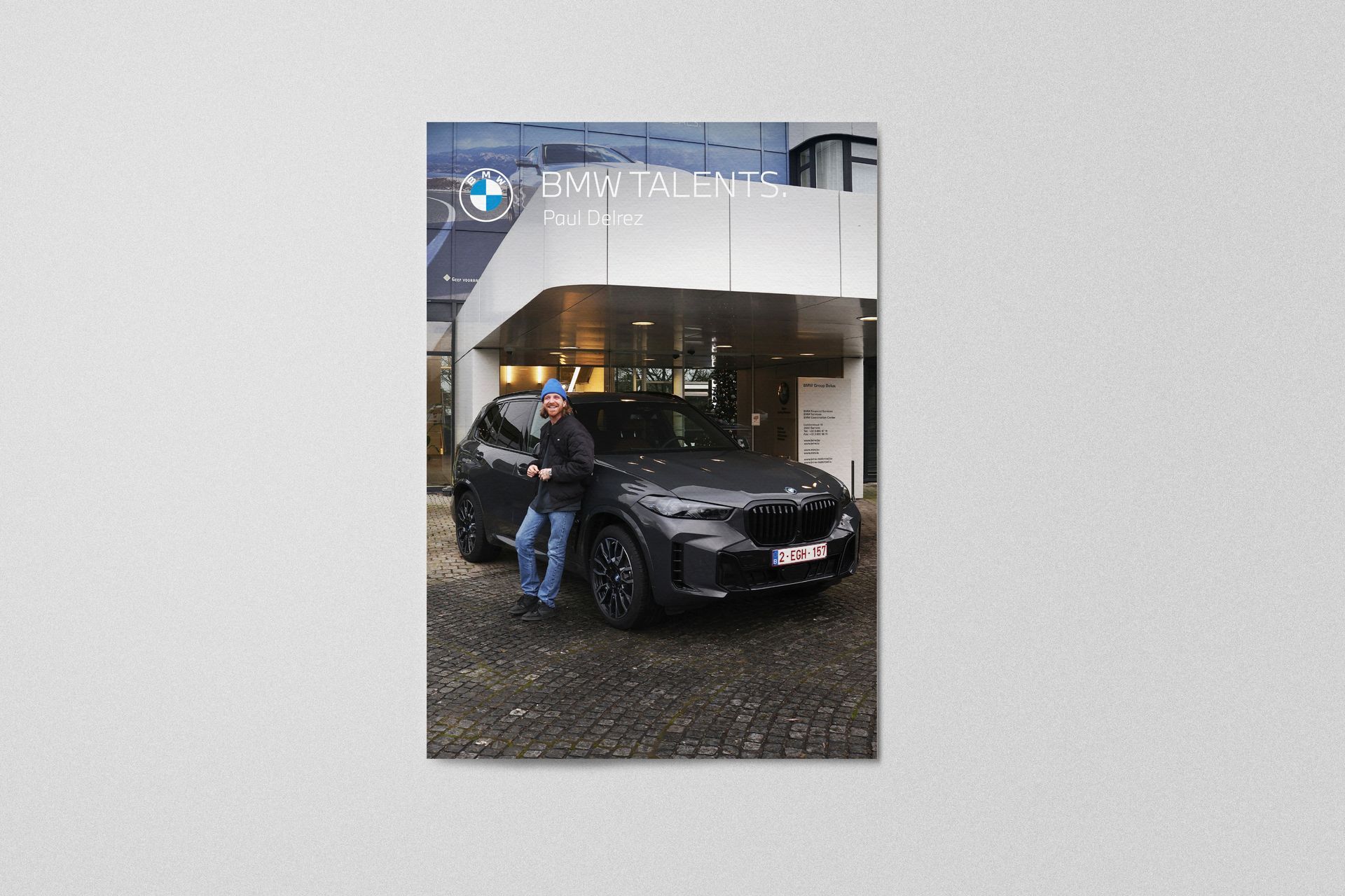 Man leunt tegen een zwarte BMW SUV voor een gebouw met een 