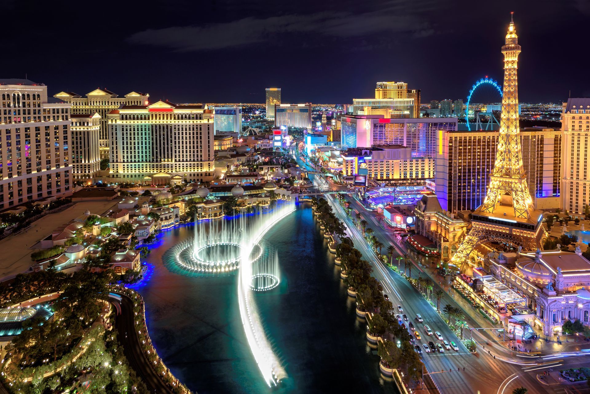 Night view of the Las Vegas Strip, featuring the Bellagio fountains in motion and the illuminated Paris Las Vegas Eiffel Tower.