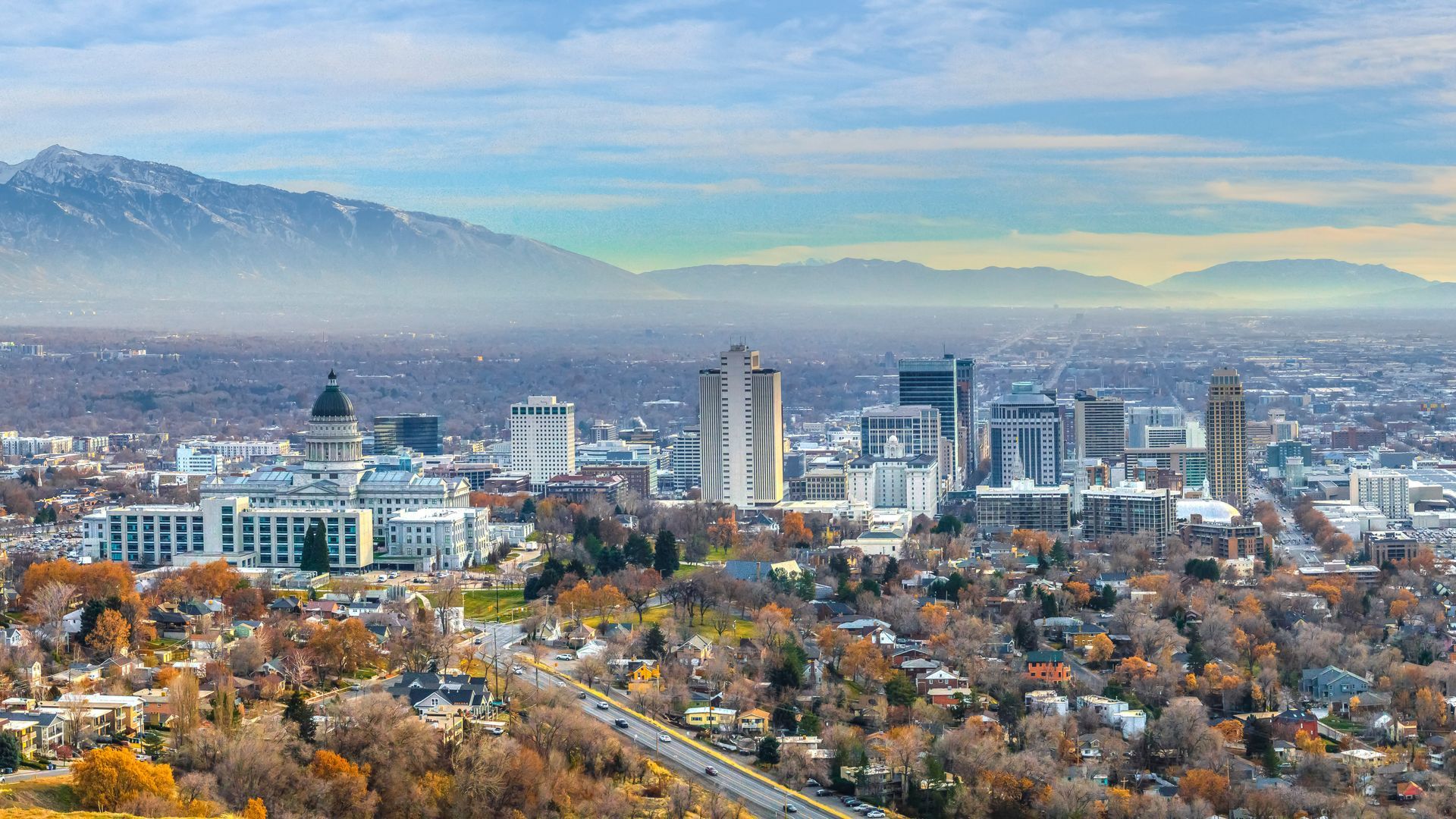Salt Lake City skyline featuring the Capitol building and high-rise architecture nestled against a mountain range.