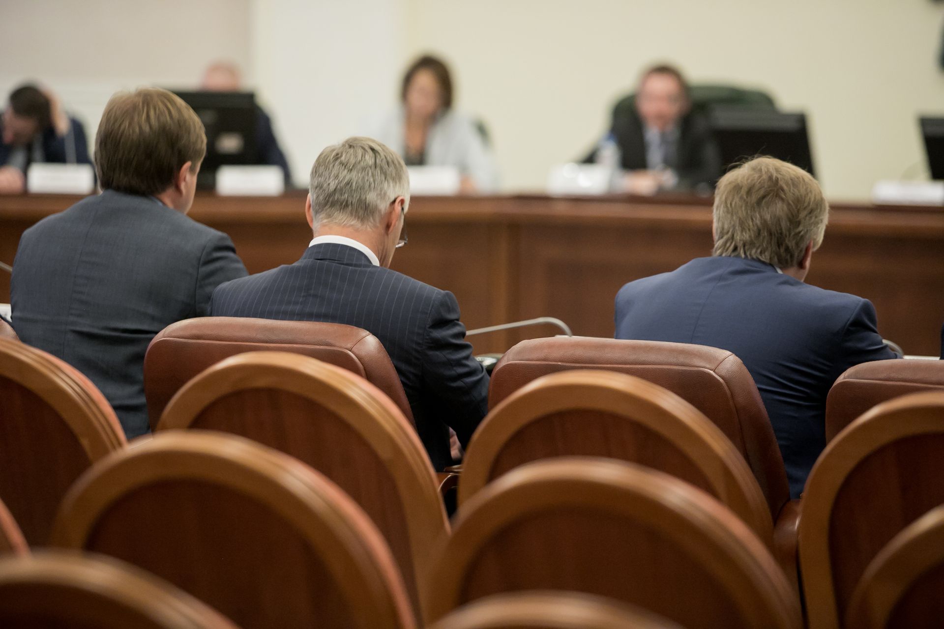 A person in a professional office setting uses a calculator and laptop near miniature house models and financial documents.