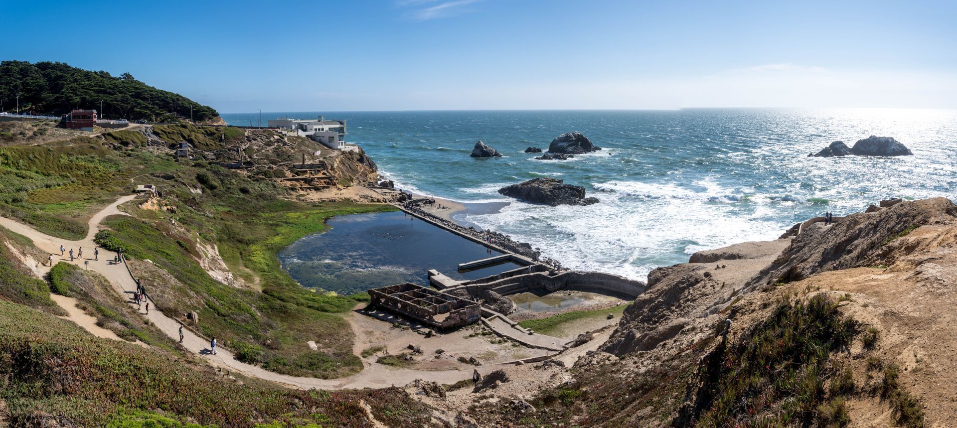 A scenic view of Sutro Baths ruins in San Francisco, featuring a partially filled tidal pool surrounded by rocky cliffs.