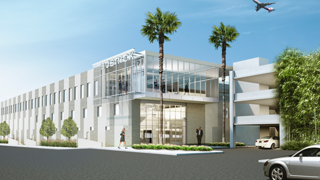 A modern, multi-story commercial building with a glass facade, palm trees, and an adjacent parking structure under a sky.