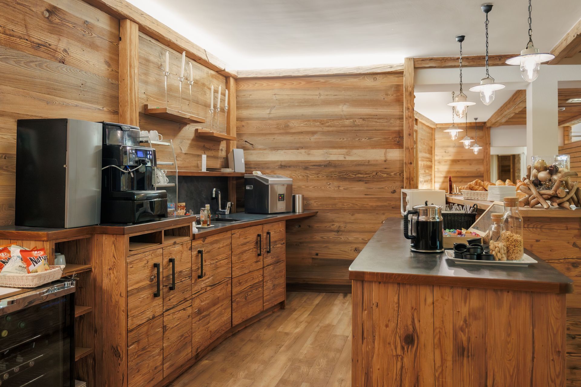 Rustic wooden kitchen with a central island, black appliances, and warm pendant lighting