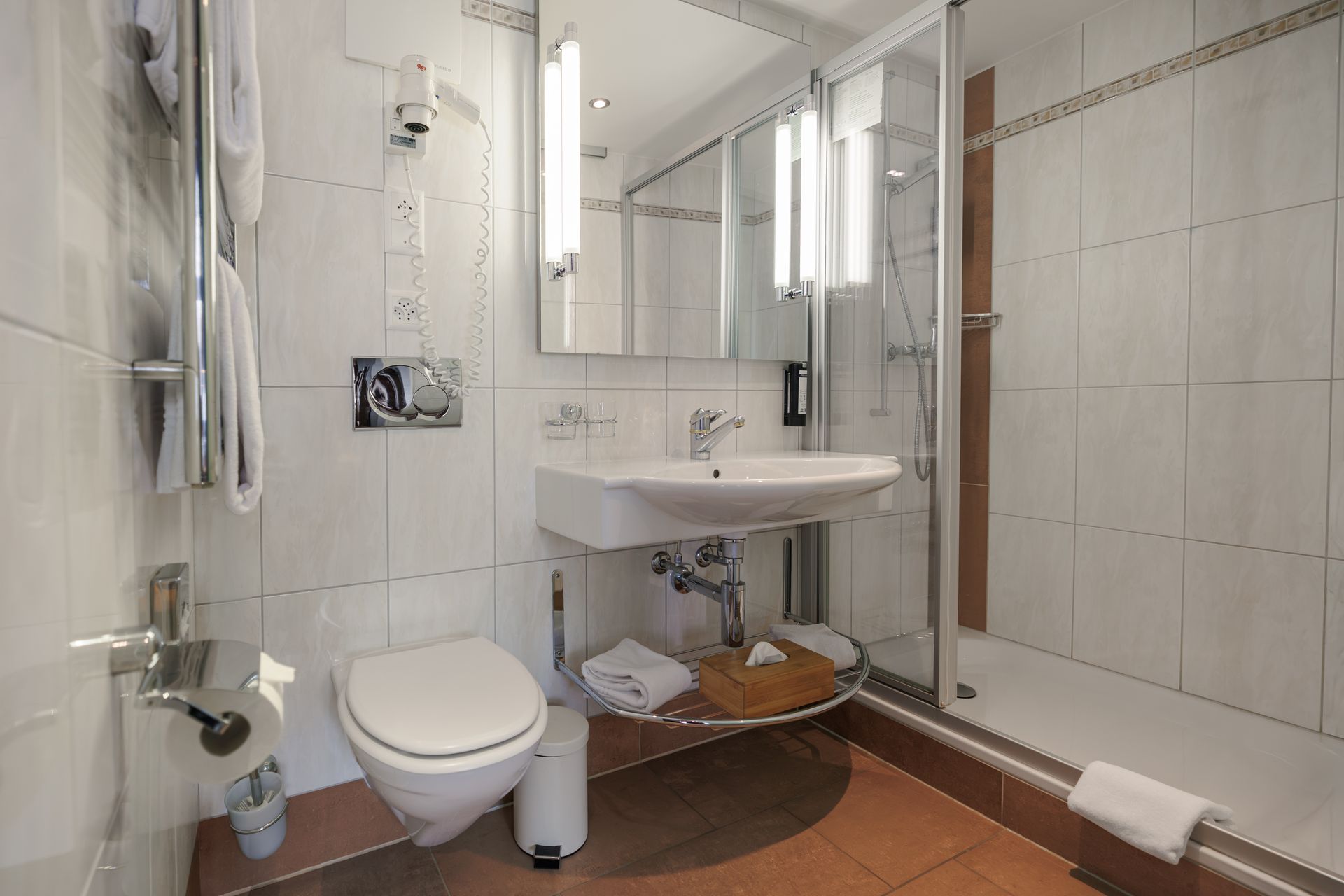 Accessible bathroom with toilet, sink, mirror, and walk-in shower with glass doors