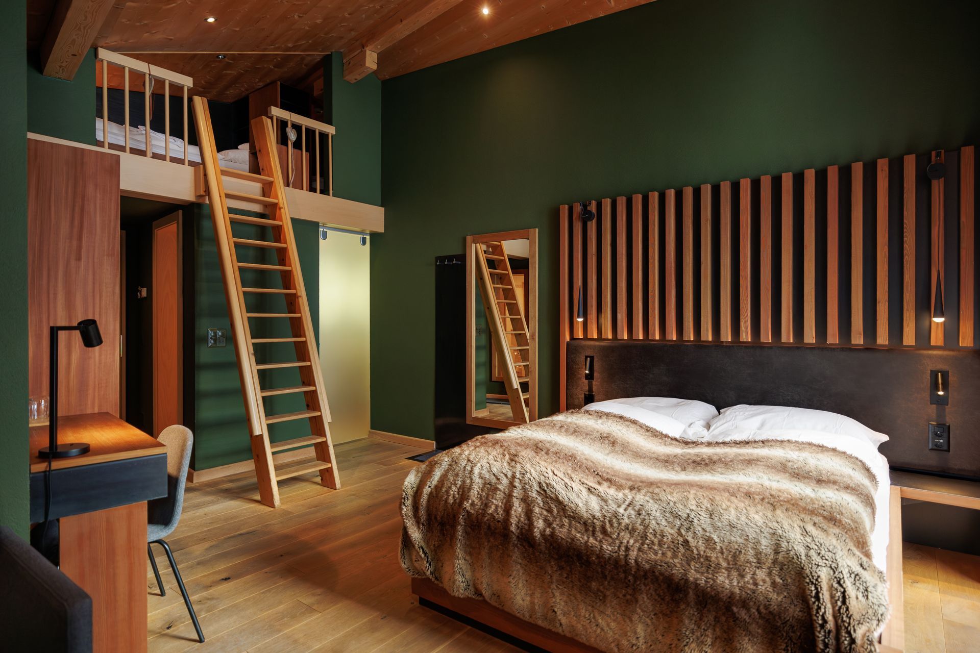 Modern loft bedroom with wood ceiling, green walls, ladder to loft, and a bed with fur throw