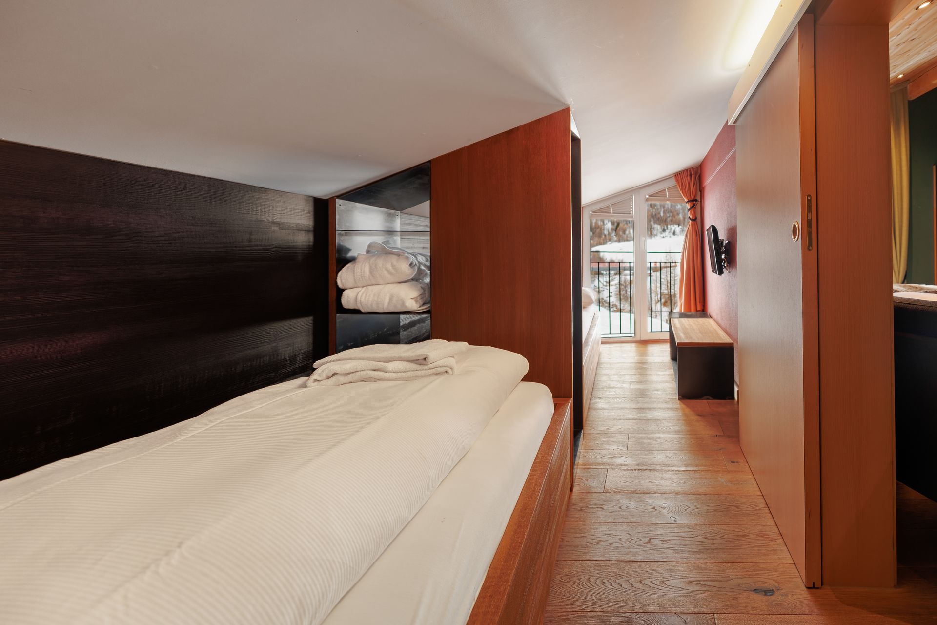 Modern hotel room with a bed, wood-paneled walls, and a window seat by the bright window.