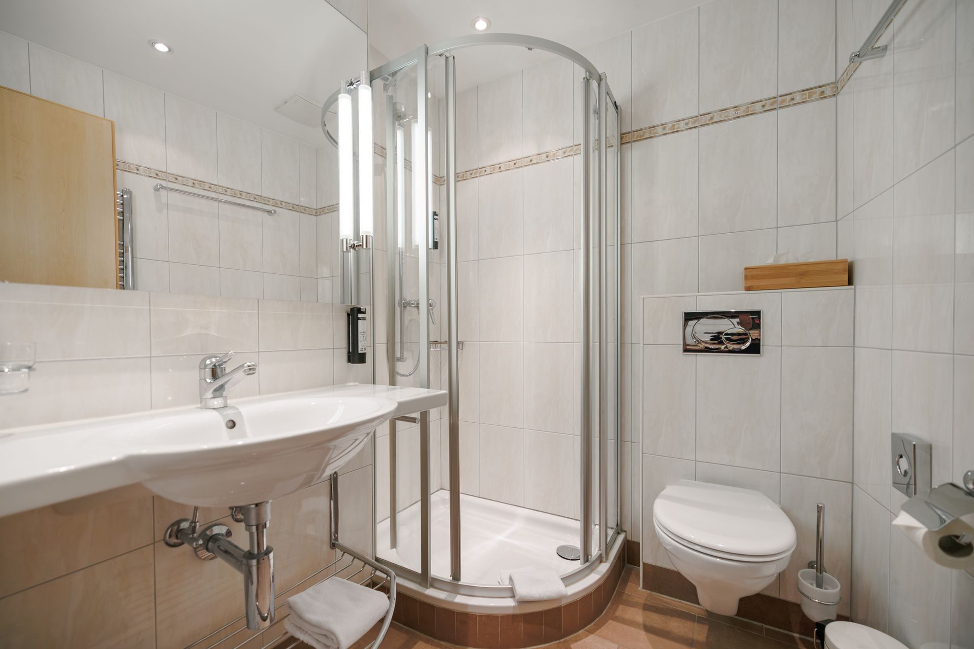 Bright white bathroom with sink, curved glass shower enclosure, and toilet