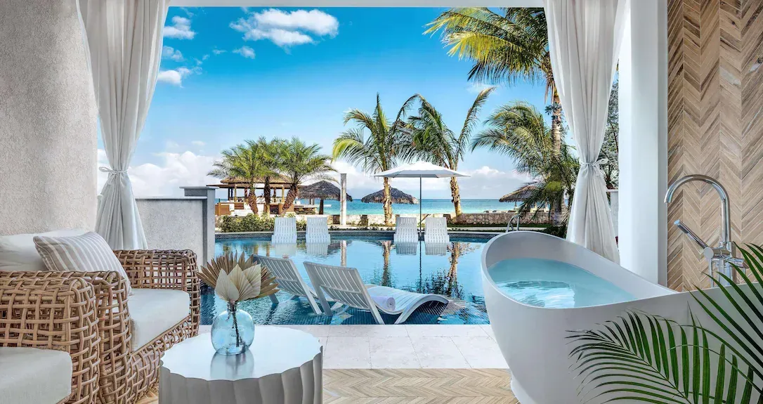 Beachfront lounge with wicker chairs, white curtains, and a pool overlooking palm trees and the ocean