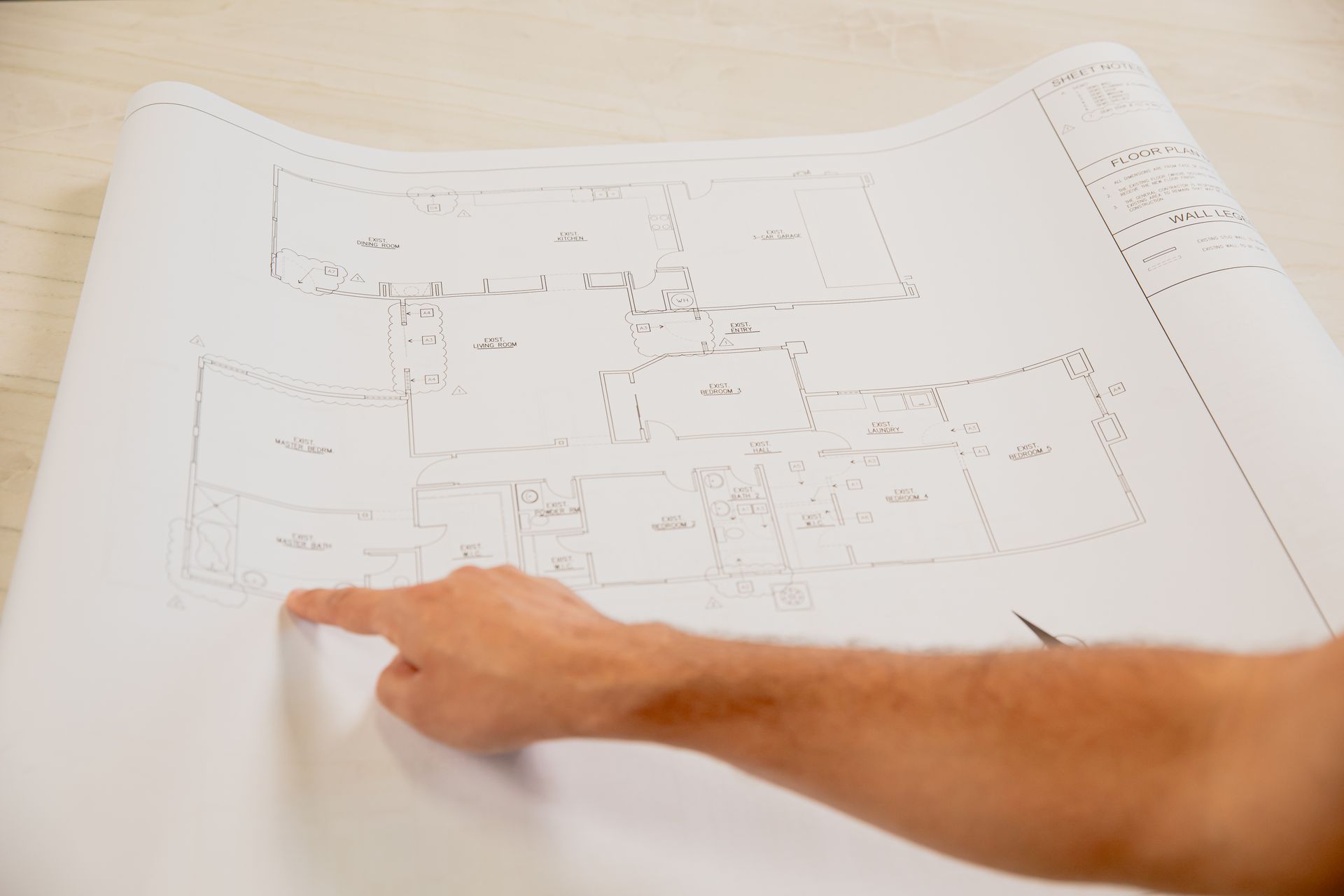 A person is pointing at a blueprint of a house.