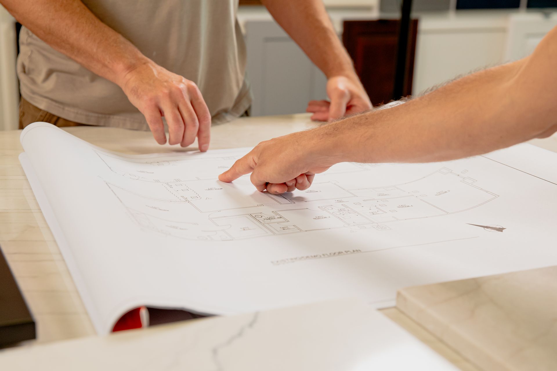 Two men are looking at a blueprint on a table.