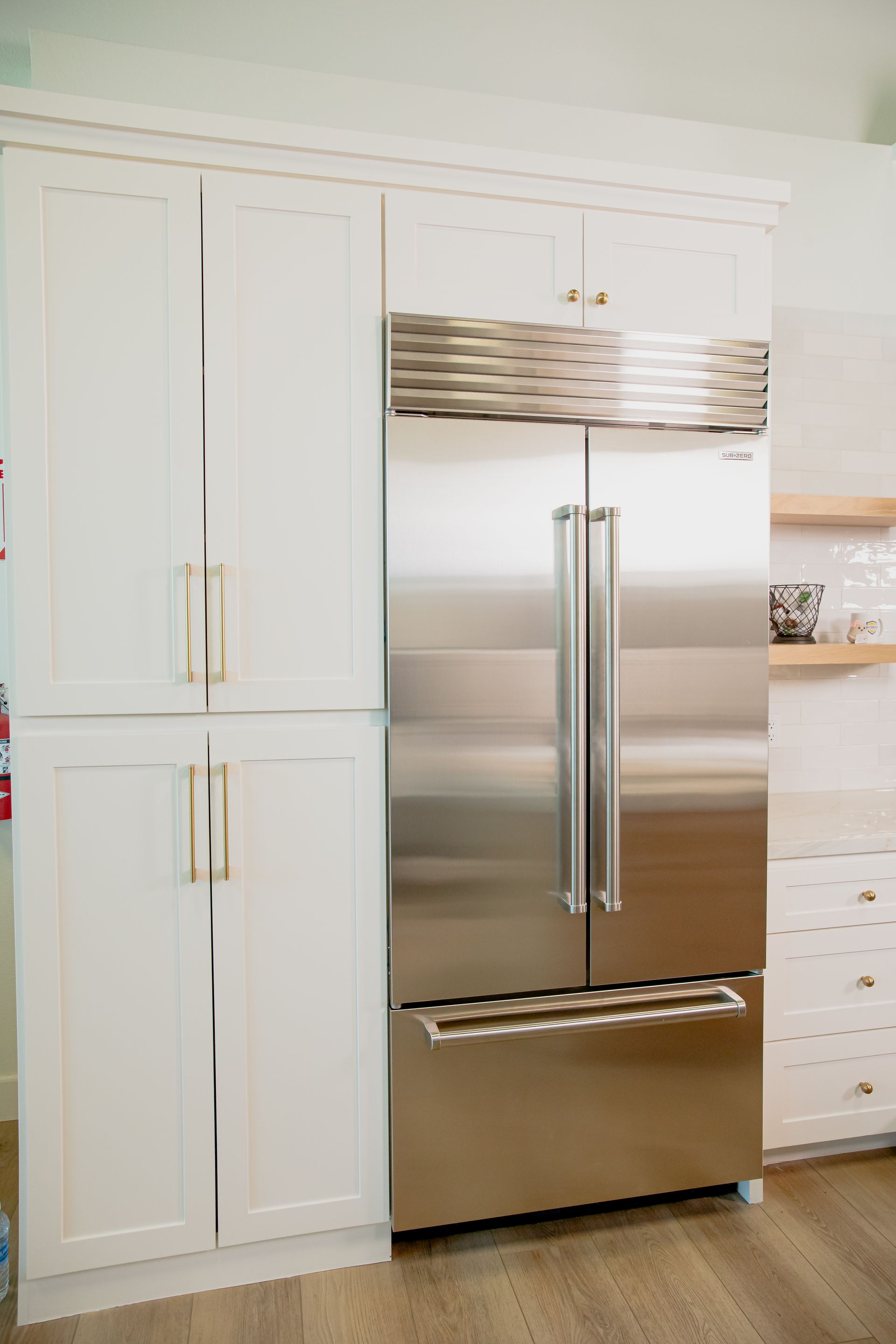A stainless steel refrigerator freezer in a kitchen with white cabinets.
