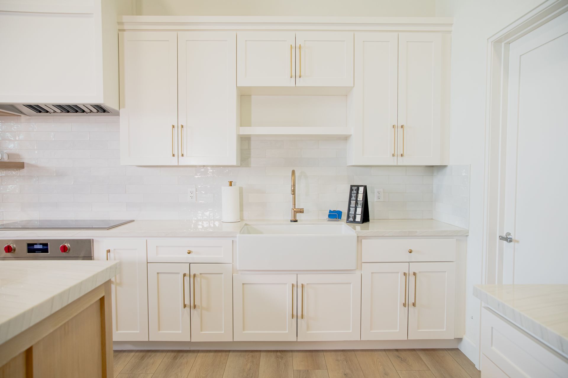 A kitchen with white cabinets , a sink , and a stove.