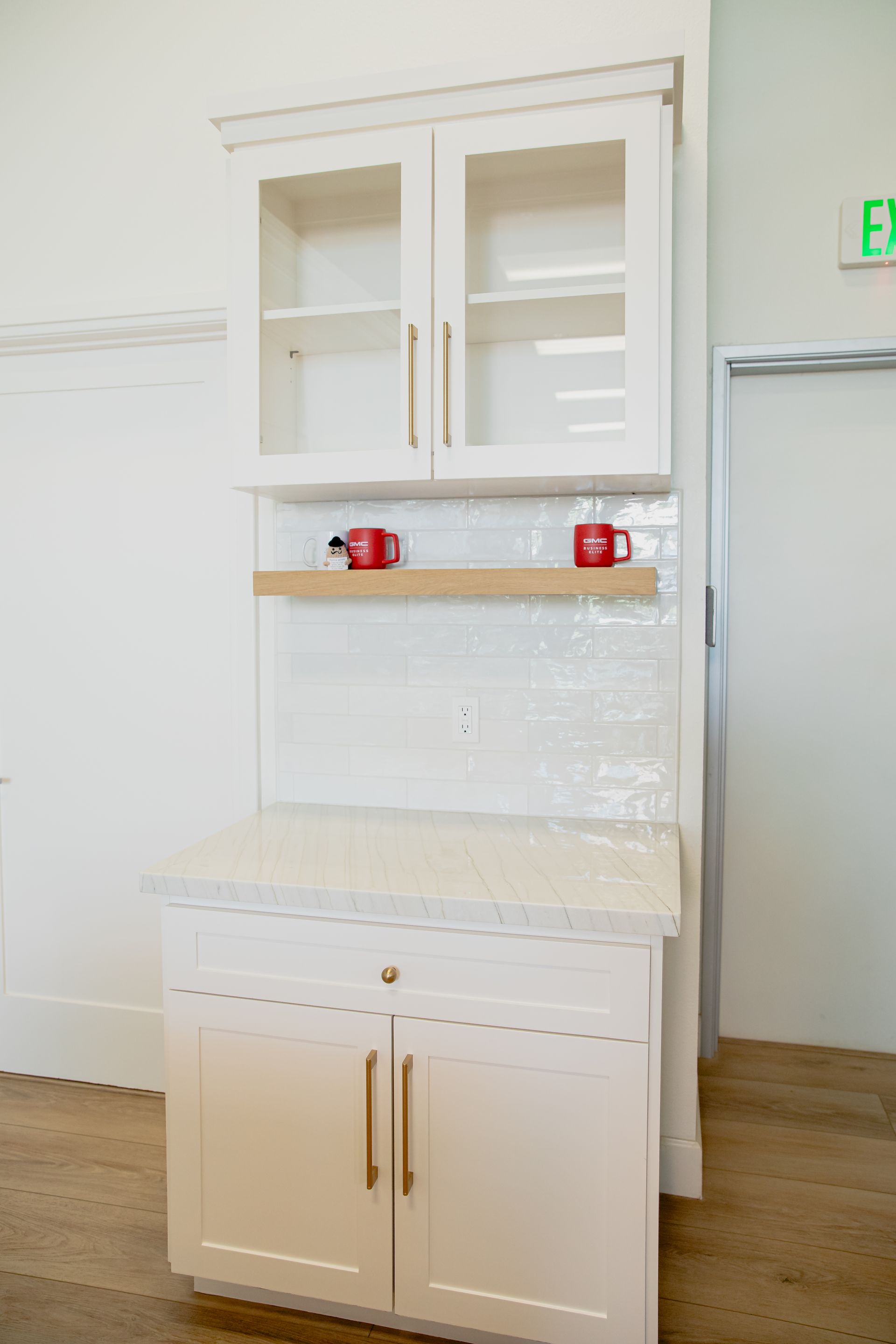 A white cabinet with glass doors and shelves in a kitchen.