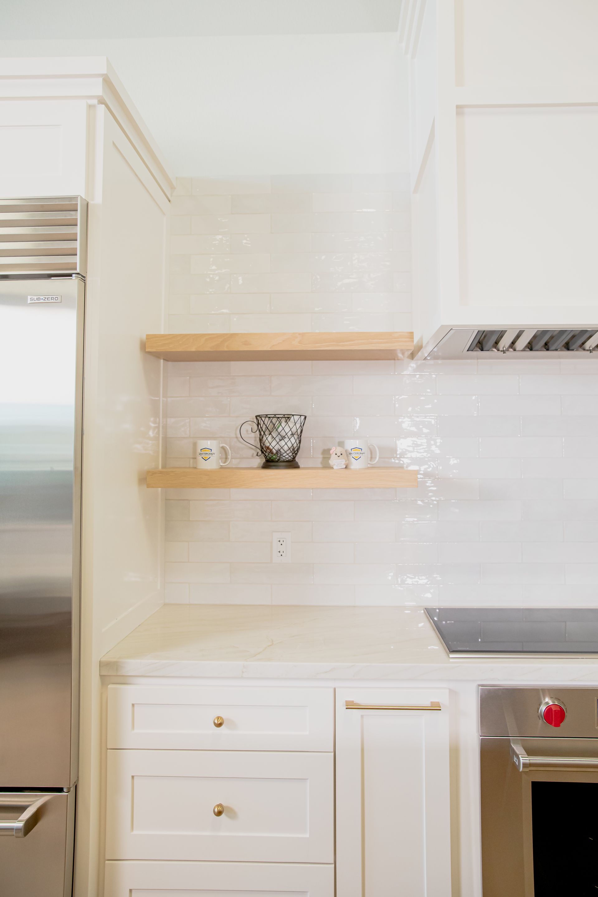 A kitchen with white cabinets , stainless steel appliances , and wooden shelves.