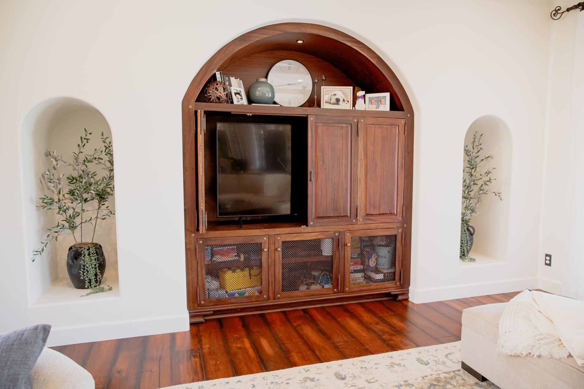 A living room with a wooden entertainment center and a flat screen tv.