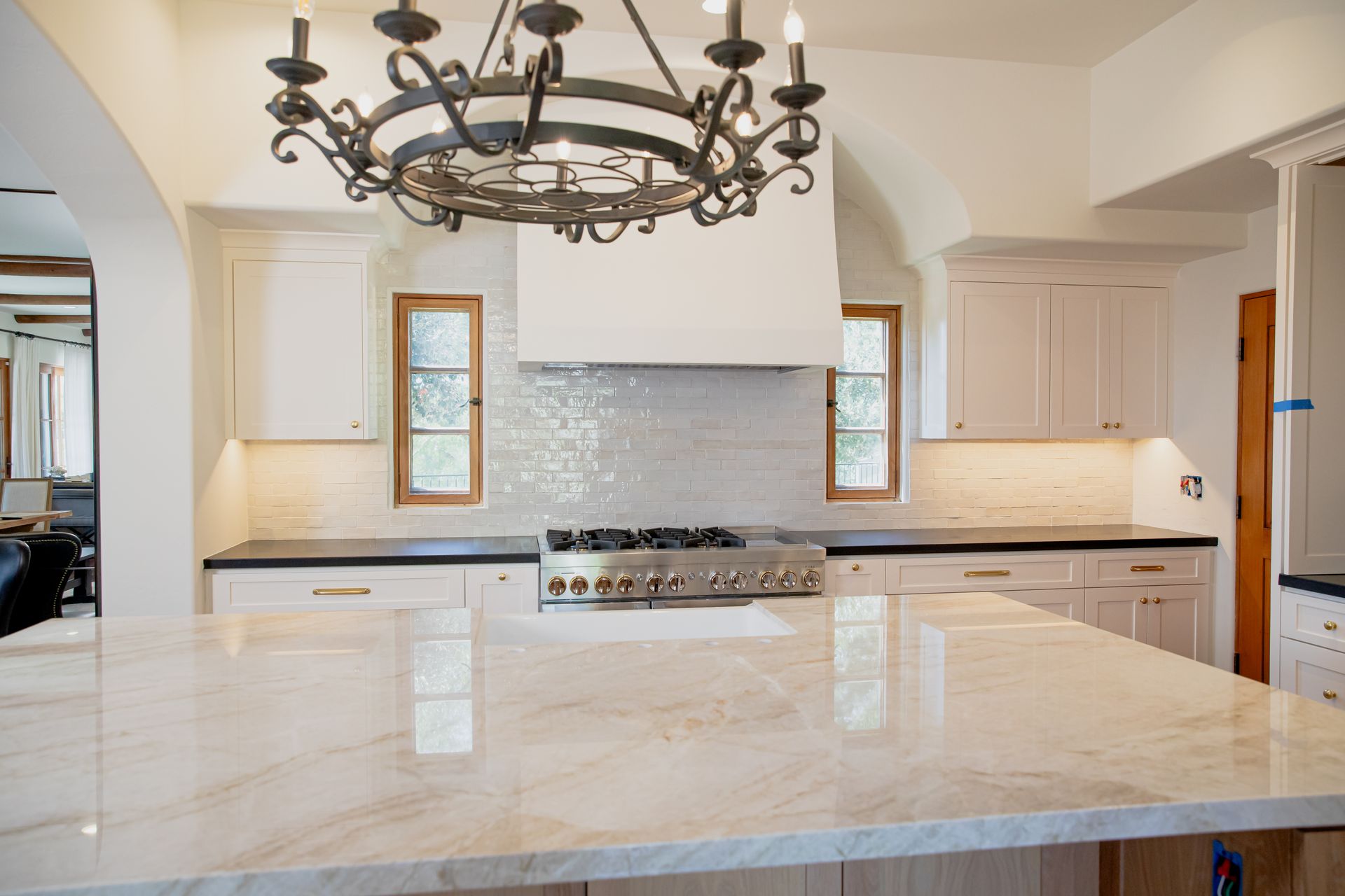 A kitchen with a stove top oven and a chandelier hanging from the ceiling.